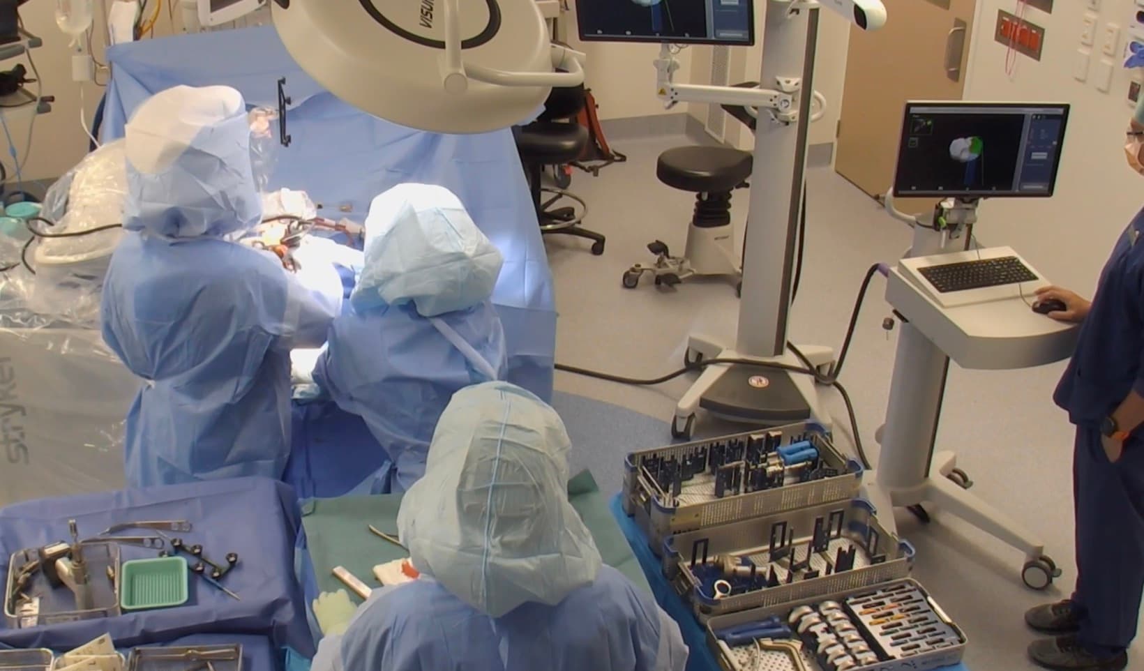 Robotic-assisted knee replacement in theatre, with the Mako planning screen alongside